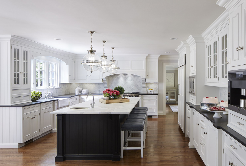 White kitchen with black countertops. Kitchen with modern globe pendant lights over black kitchen island with white marble countertop