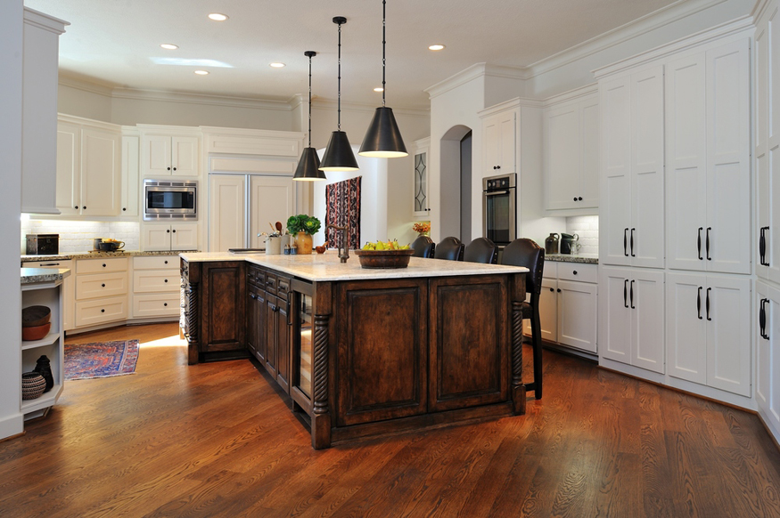 White kitchen with dark wood island with hickory wood floors and black pendant lights