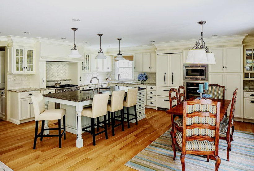 White kitchen with dining room. Kitchen with white pendant light over kitchen island with marble countertop