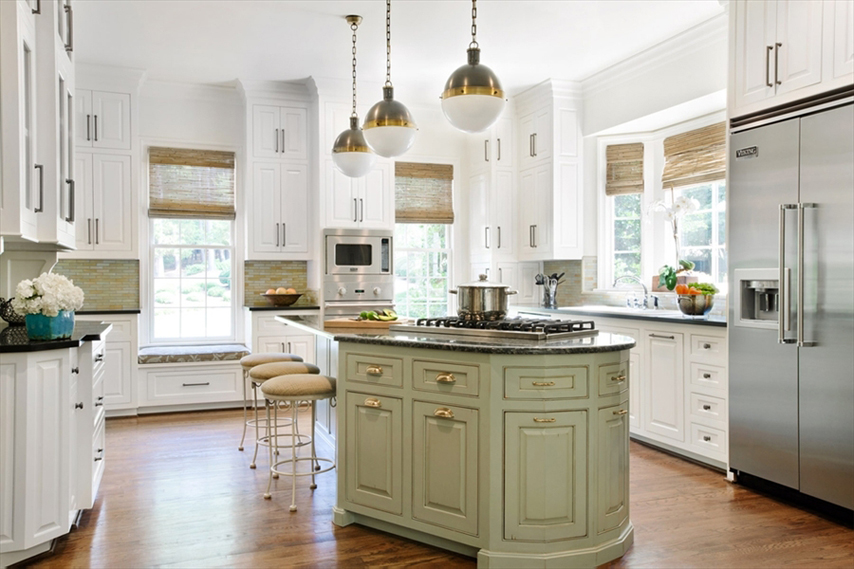 White kitchen with light wood floors. Kitchen with bar stools with white pendant lights fixture over green kitchen island with black marble countertop