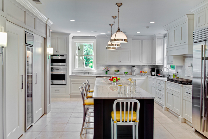 White kitchen with yellow leather bar stools. Kitchen with white dome pendant lights over dark kitchen island with marble countertop 