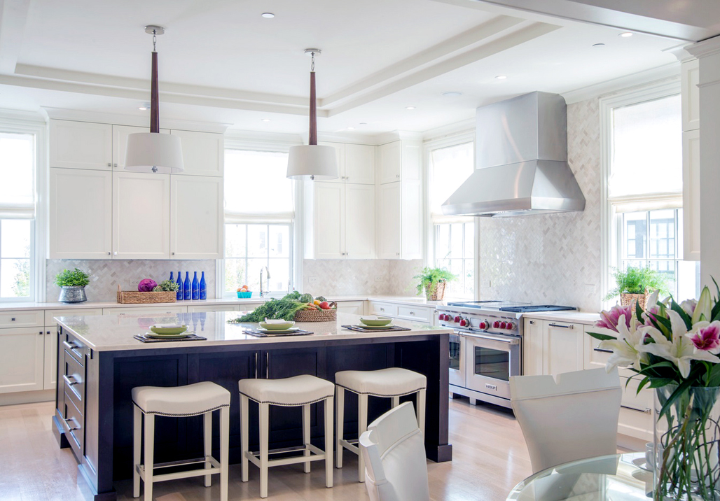 White kitchen with leather saddle bar stools. Kitchen with drum pendant lights over navy kitchen island with marble countertops