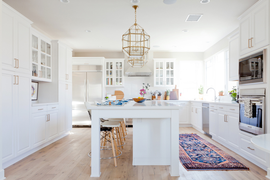 White kitchen with blue bohemian rug and modern pendant lights