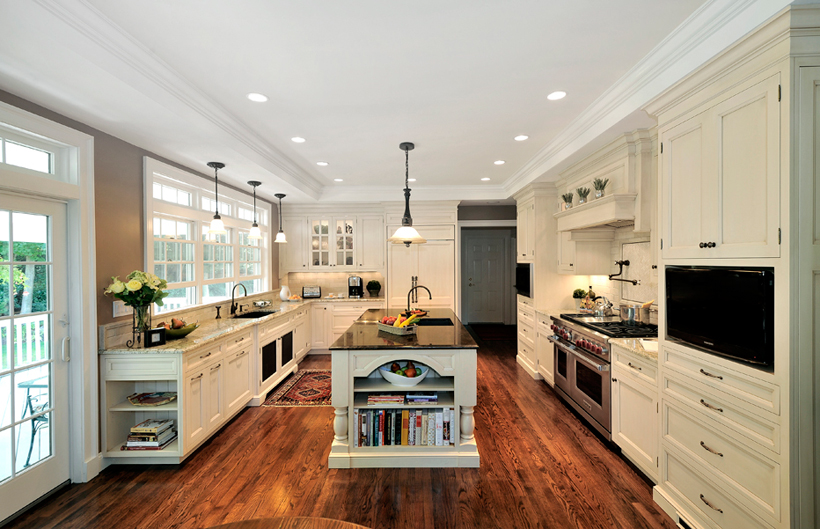 White kitchen with white pendant lights over white kitchen island with black countertop