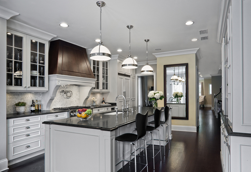 White kitchen with modern black bar stools and white kitchen island. Kitchen with white dome pendant lights over white kitchen island with black countertop