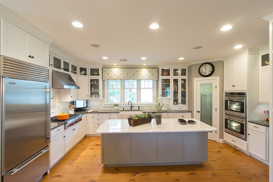 White kitchen with light wood floors and gray kitchen island with marble countertops 