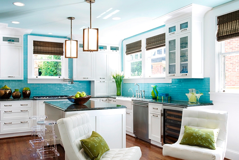 Small white kitchen with blue subway tile backsplash and galss bar stools. Kitchen with tube pendant lights over kitchen island with black marble countertops