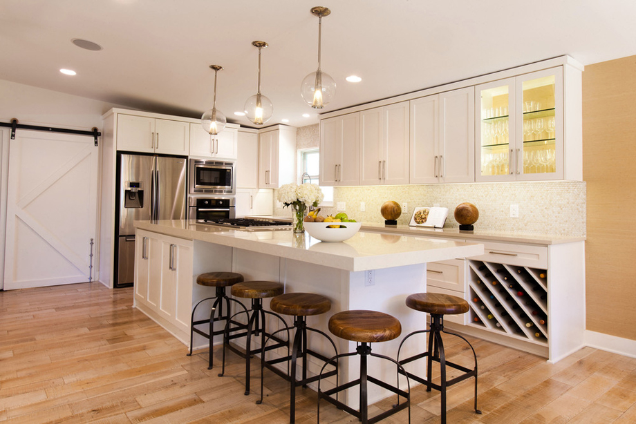 White kitchen with industrial bar stools and white kitchen island. Kitchen with bubble glass pendant lights over white kitchen island with laminate countertops