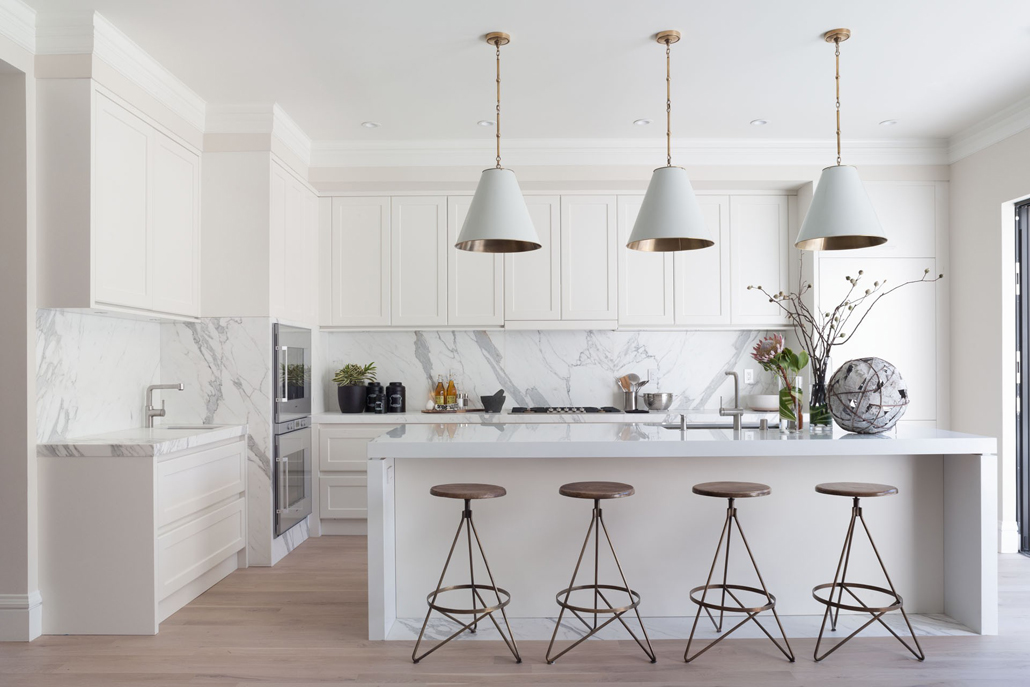 White kitchen with marble tile backsplash and white pendant lights 