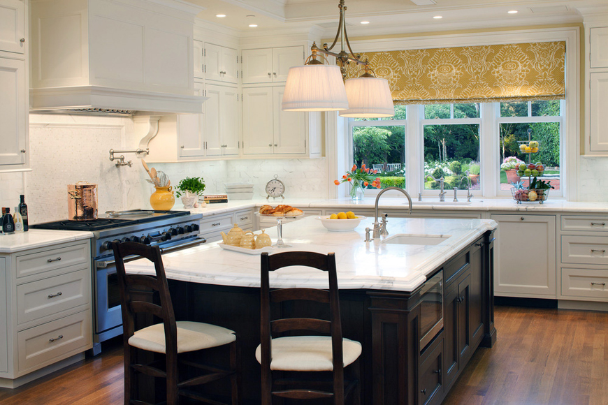 White kitchen with white drum pendant lights over dark kitchen island with marble countertops