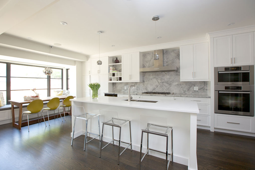 White kitchen with gray marble backsplash and dark wood flooring 