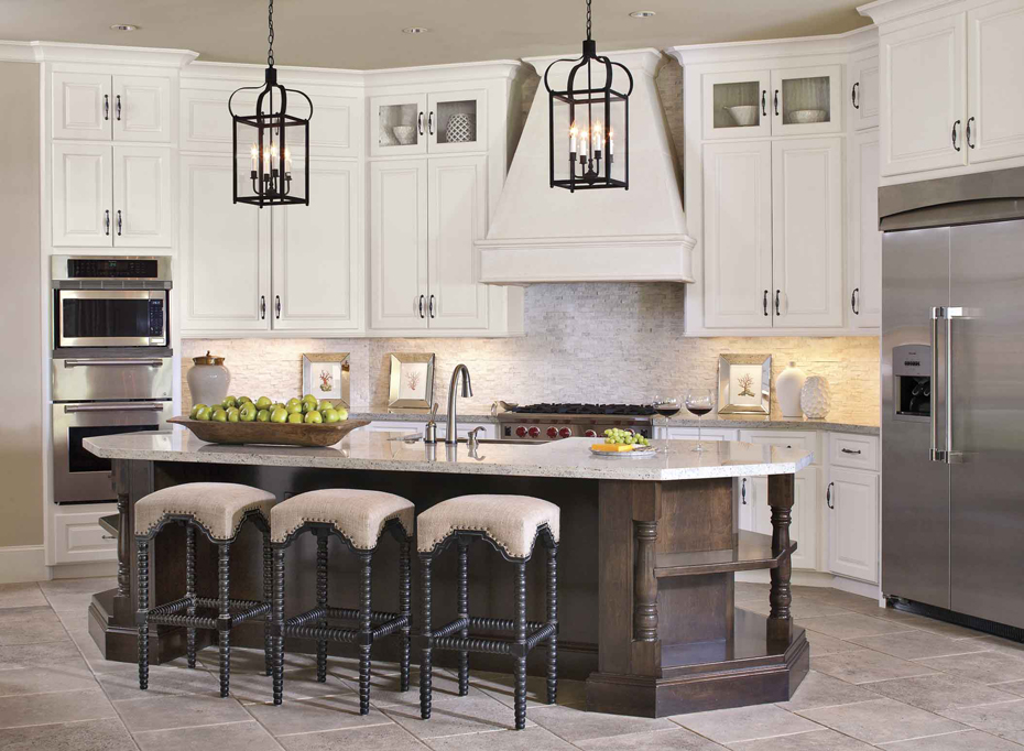 Wite kitchen with linen backless bar stools. Kitchen with lantern pendant lights over wooden kitchen island with marble countertops