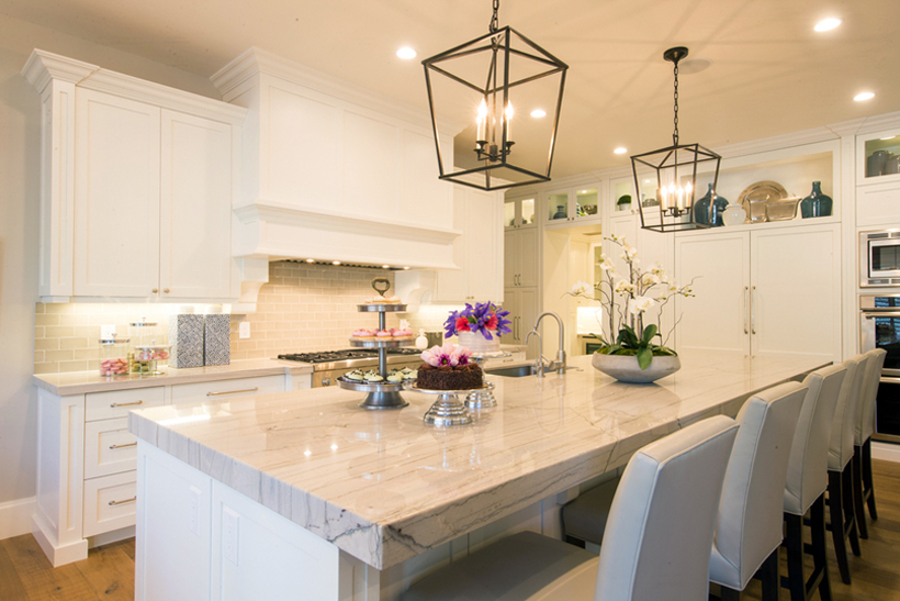 Wite kitchen with white bar stools and lantern pendant lights. Kitchen with lantern pendant lights over white kitchen island with marble countertops