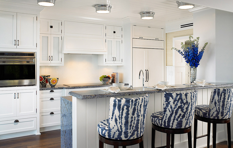 White kitchen with kitchen island with granite countertop and blue bar stools 