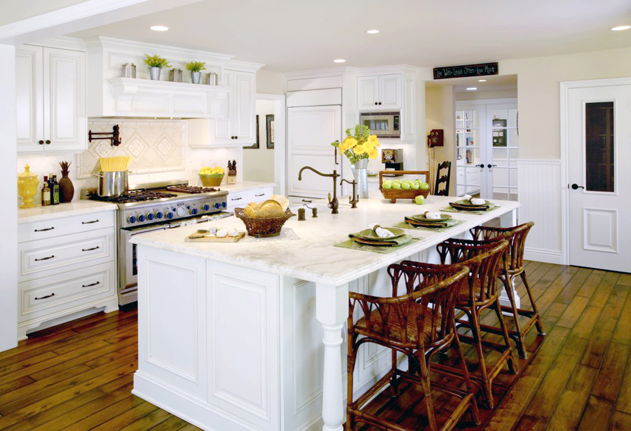 White kitchen with rattan bar stools and white kitchen island with marble countertop