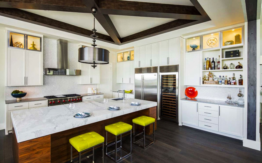 White kitchen with yellow bar stools and wooden kitchen island. Kitchen with drum shade pendant light over wooden kitchen island with marble countertop