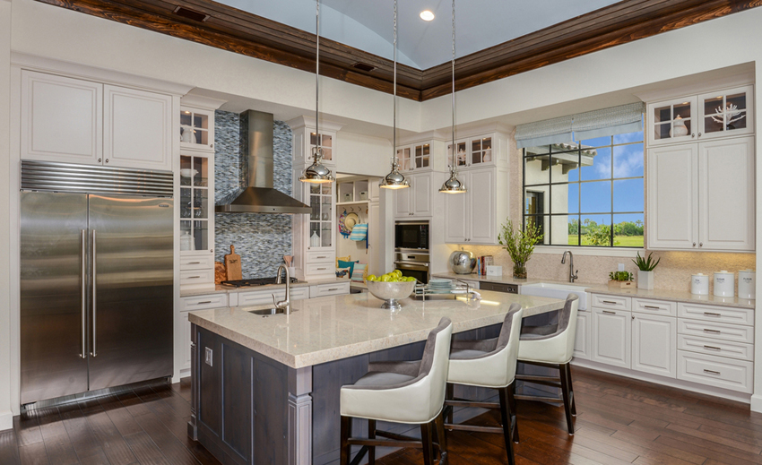 White kitchen with white swivel bar stools. Kitchen with chrome pendant lights over gray kitchen island with marble countertops