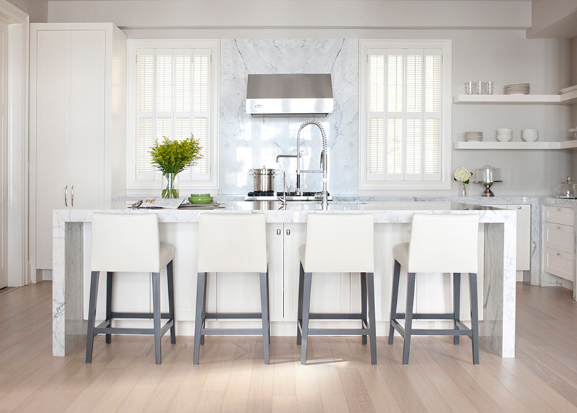 White kitchen with open shelves and marble backsplash. Kitchen with white bar stools and white kitchen island with marble countertops