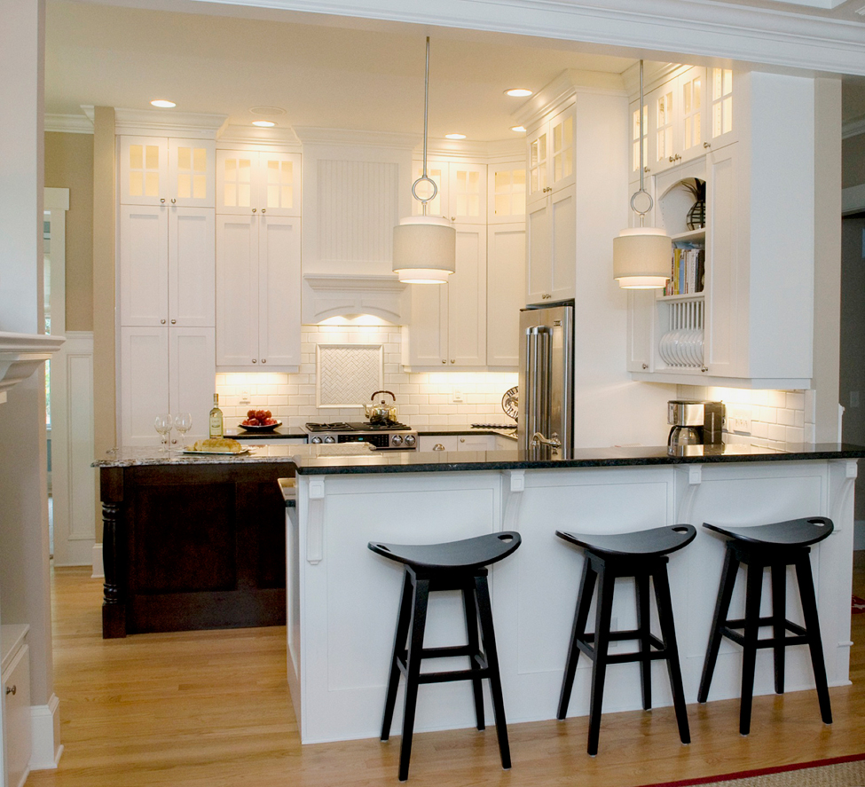 Small white kitchen with under cabinet lighting. Kitchen with black bar stools and drum shade pendant lights