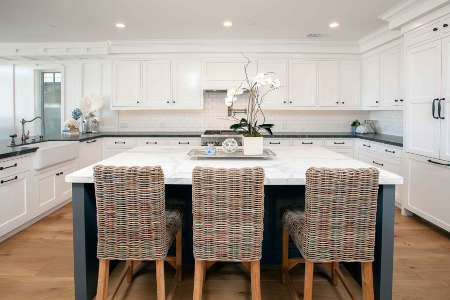 White kitchen with wicker rattan bar stools. Kitchen with large kitchen island with white cabinet