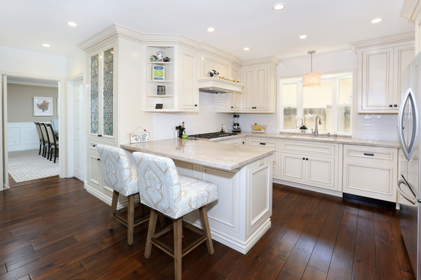 Small white kitchen with dark hardwood flooring and white bar stools
