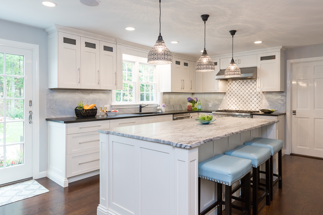 White kitchen light blue bar stools and hardwood floors. Kitchen with dome pendant lights over white kitchen island with marble countertop