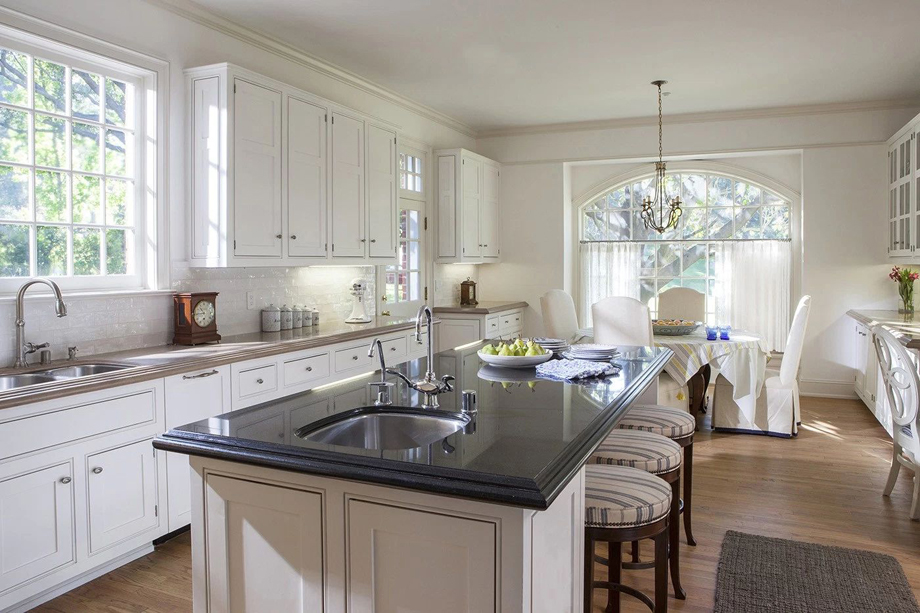 White kitchen with dining room combination with dark quartz countertop and bar stools