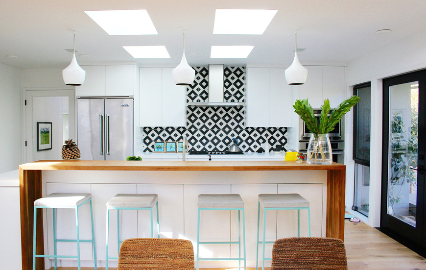 Cool white kitchen with turquoise bar stools. Kitchen with black white backsplash tile and white pendant lights over wood kitchen island