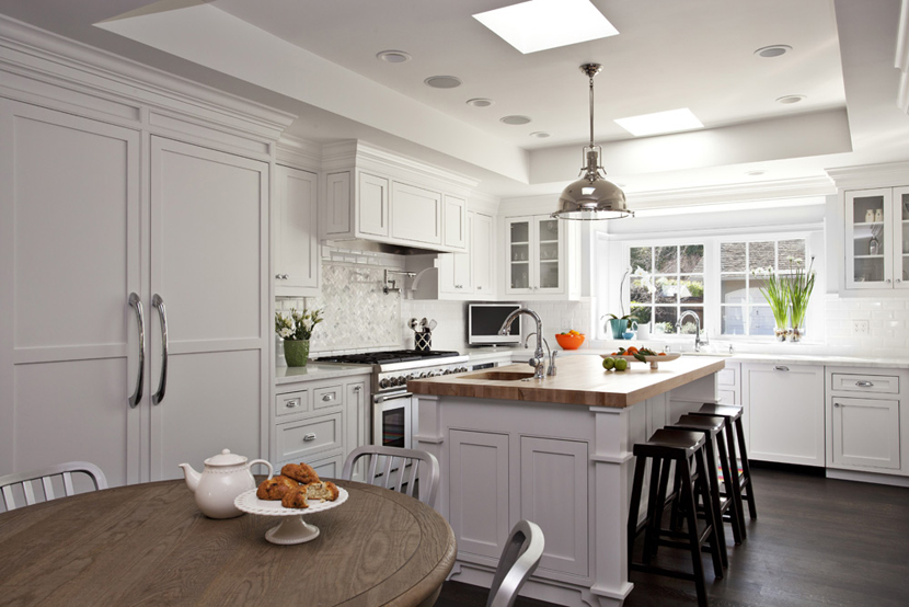 White kitchen with dark wood bar stools. Kitchen with chrome dome pendant light over kitchen island with wooden countertops