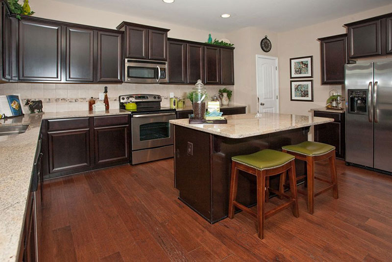 Dark brown cabinets with river white granite