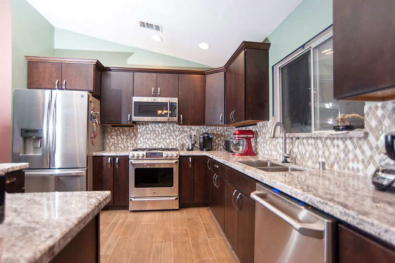 Brown kitchen cabinets with bianco romano granite countertops and backsplash